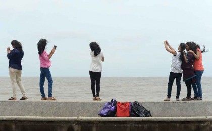 (FILES) In this photograph taken on June 15, 2015, young Indian couples take 'selfies' on Marine Drive promenade in Mumbai.   Mumbai police said January 12, 2016, that they have identified 16 dangerous selfie spots across the Indian city after a man drowned trying to save a girl who fell into the sea while taking a photo of herself. The spots include the major tourist attractions of Girgaum Chowpatty beach and Marine Drive promenade as well as the site where the 18-year-old girl slipped last week, deputy commissioner Dhananjay Kulkarni told AFP.  AFP PHOTO/Indranil MUKHERJEE/FILESINDRANIL MUKHERJEE/AFP/Getty Images