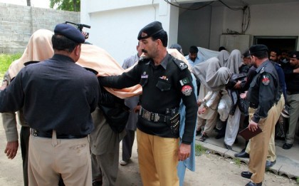 Pakistani police officers escort members of a local tribal council, with their faces covered outside a court in Abbottabad, Pakistan, Thursday, May 5, 2016. Pakistani police have arrested 13 members of a local tribal council for burning alive a girl, who had helped one of her friends elope to marry a man of her choice. (AP Photo/Aqeel Ahmed)